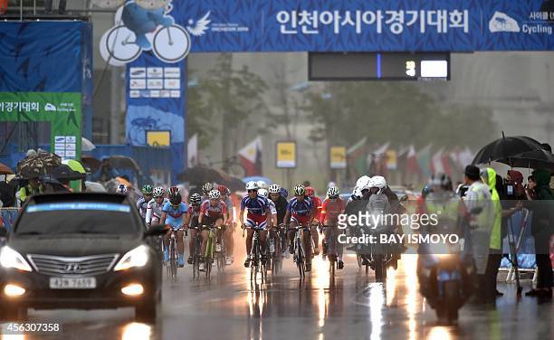 Cyclists compete in the rain during the women's road race on the Songdo Road Cycling Course during the 17th Asian Games in Incheon on September 29,...