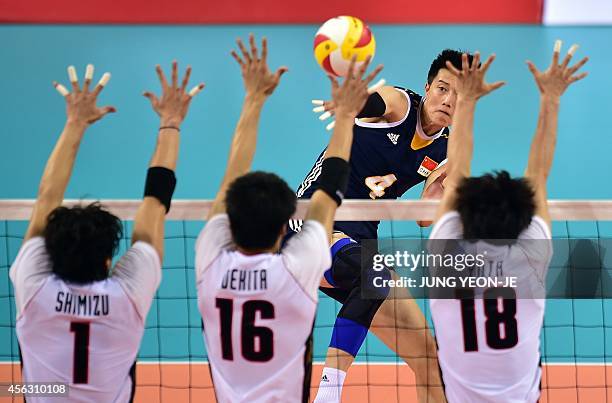 China's Zhang Chen spikes as Japan's Kunihiro Shimizu , Takashi Dekita and Yuta Yoneyama block in the men's volleyball play off event during the 2014...