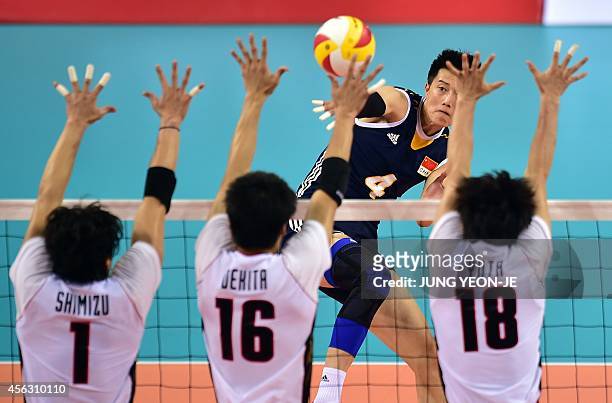 China's Zhang Chen spikes as Japan's Kunihiro Shimizu , Takashi Dekita and Yuta Yoneyama block in the men's volleyball play off event during the 2014...