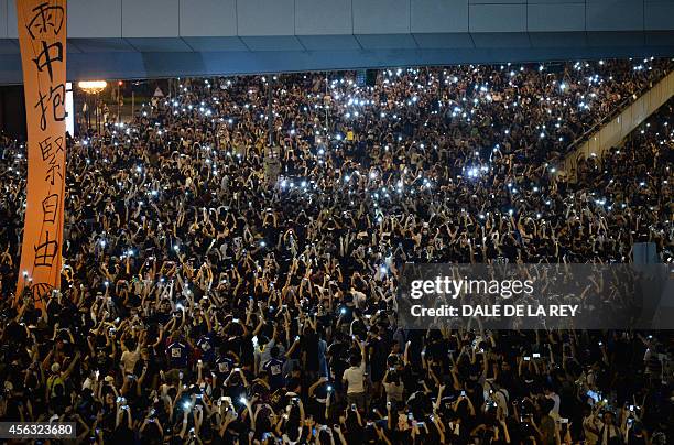 Pro-democracy demonstrators hold up their mobile phones during a protest near the Hong Kong government headquarters on September 29, 2014. The ranks...