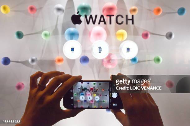 Woman photographs a window display of the Apple watch during the unveiling of the new and highly anticipated product at Saint-Honore street in Paris...