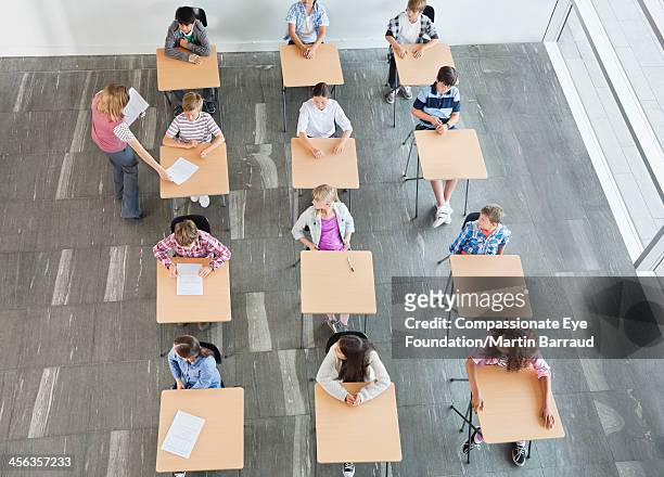 teacher handing out test papers to students - eye exam stockfoto's en -beelden