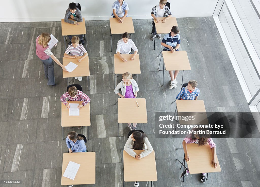 Teacher handing out test papers to students