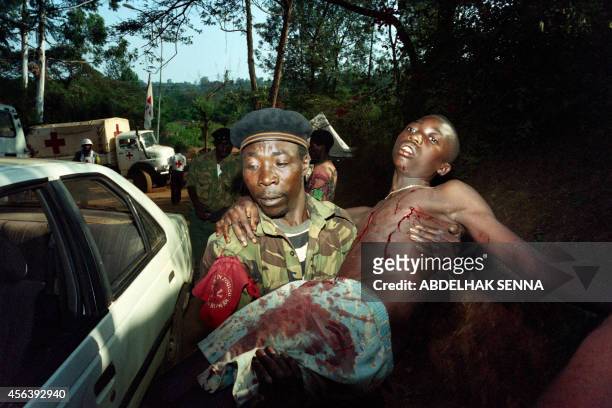 Militiaman wounded by rebel mortar shrapnel is carried by a comrade to the Red Cross hospital on June 19, 1994 in Kigali. On April 6 the death of the...
