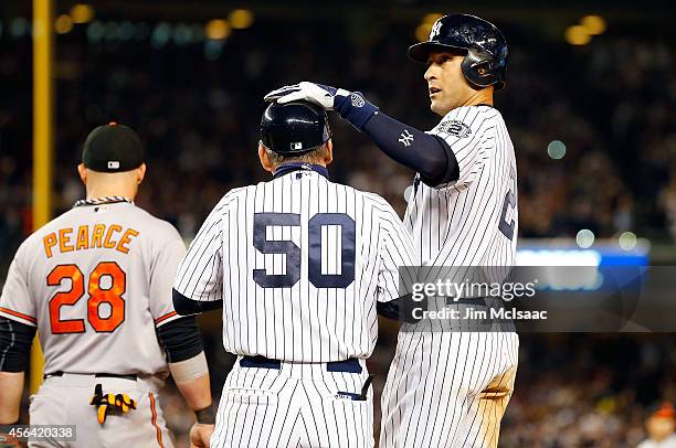 Derek Jeter of the New York Yankees stands at first base in seventh inning against the Baltimore Orioles with first base coach Mick Kelleher at...