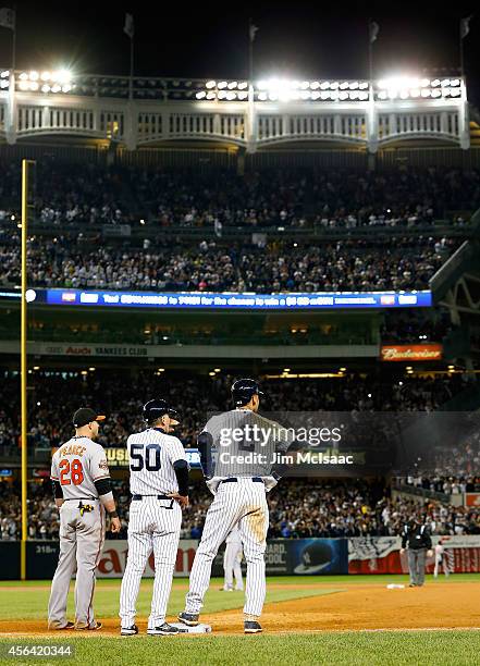 Derek Jeter of the New York Yankees stands at first base in seventh inning against the Baltimore Orioles with first base coach Mick Kelleher at...