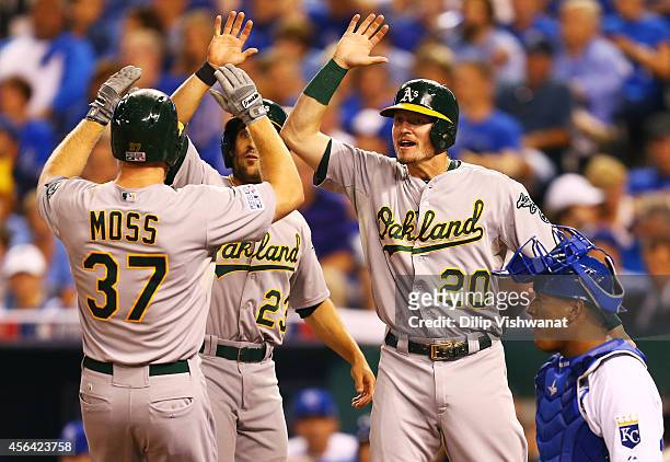 Josh Donaldson, Sam Fuld and Brandon Moss of the Oakland Athletics celebrate after Moss' three-run home run in the sixth inning against the Kansas...