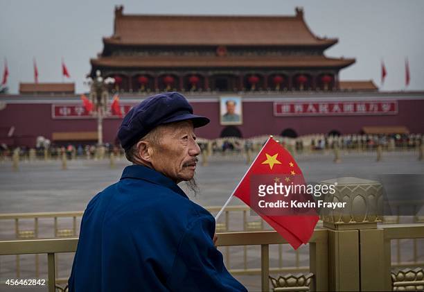 An elderly Chinese man holds a flag as he stands in Tiananmen Square on the 65th National Day on October 1, 2014 in Beijing, China. The day marks the...