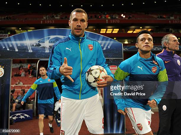 Lukas Podolski and Alexis Sanchez of Arsenal walk out for the warm up before the UEFA Champions League group match between Arsenal and Galatasaray on...