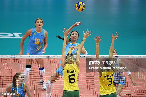Sana Anarkulova of Kazakhstan spikes as Lins Danielle and Thaisa Menezes of Brasil block during the FIVB Women's World Championship pool F match...