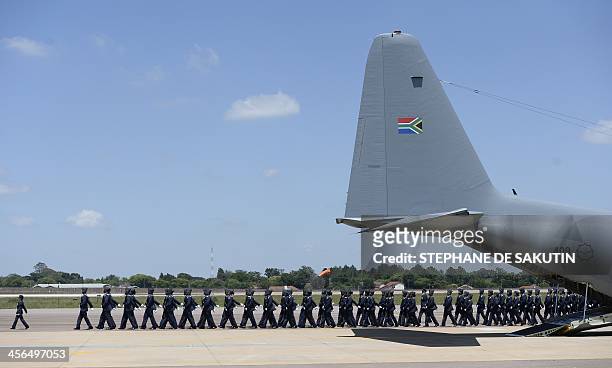 Troops march near the plane which will transporte the remains of South African former president Nelson Mandela to Mthatha on December 14, 2013 at the...