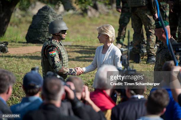 German Defence Minister Ursula von der Leyen shakes hands with a Peshmerga fighter as German General Gert-Johannes Hagemann looks on, on October 02,...