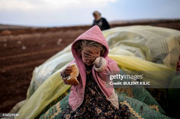 Syrian Kurdish woman wait with her daughter near the Syria border at the southeastern town of Suruc in the Sanliurfa province after crossing the...