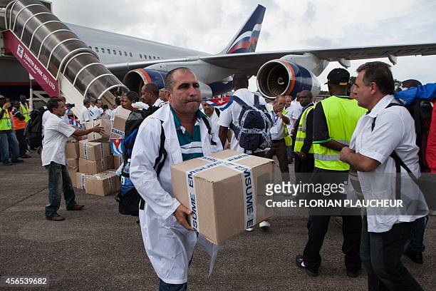 The first members of a team of 165 Cuban doctors and health workers unload boxes of medicines and medical material from a plane upon their arrival at...