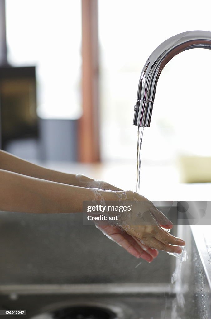 Female washing hands in the kitchen