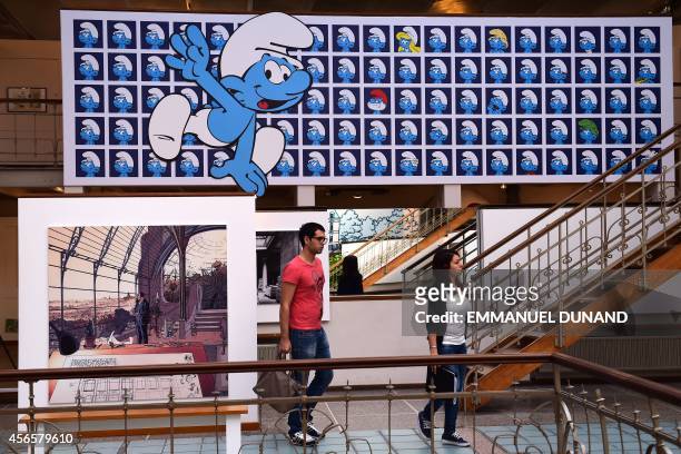 Visitors walk past a panel exhibiting characters from the Belgian comic series "The Smurfs" created by Belgian cartoonist Peyo , and a plate from the...