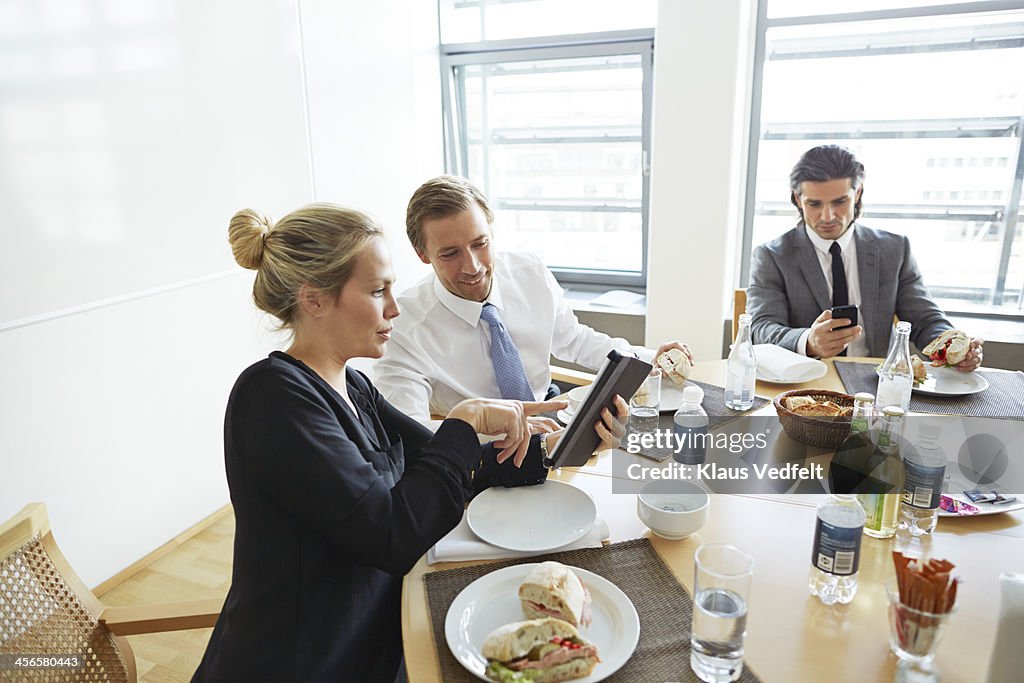 Business people using tablet at lunch meeting