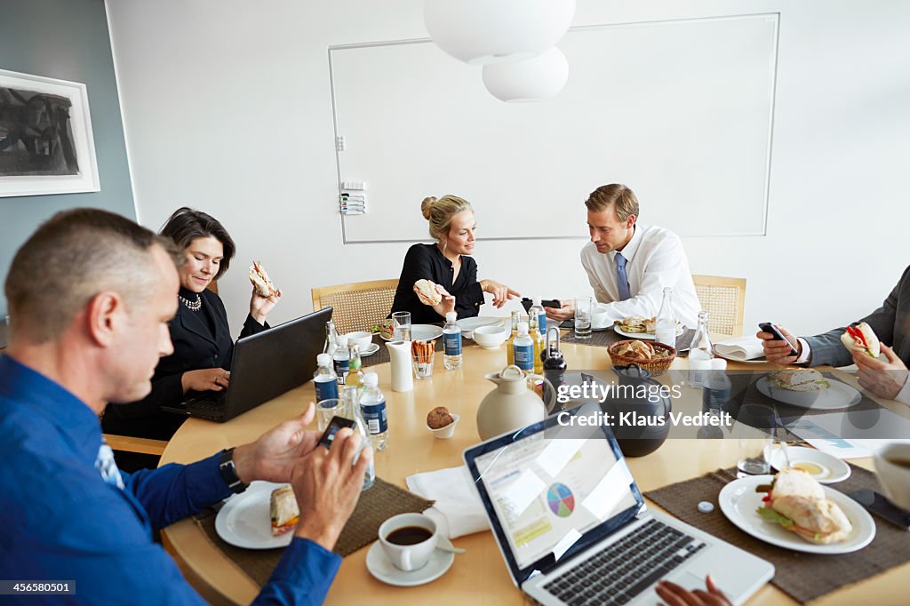 Business people using technology at lunch meeting
