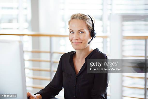 woman with headset smiling to camera - telephone hotline stock pictures, royalty-free photos & images