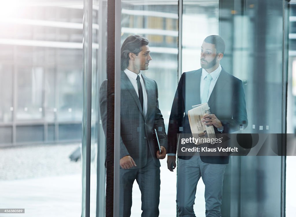 Businessmen walkin & talking threw swing door