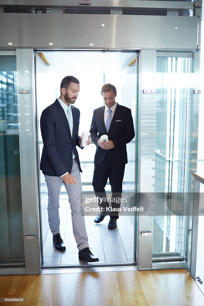 Business people walking out of elevator