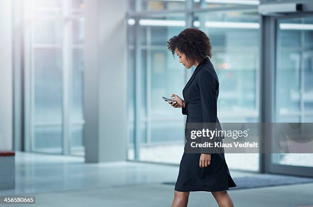 businesswoman checking her phone, while walking - man walking phone stock-fotos und bilder