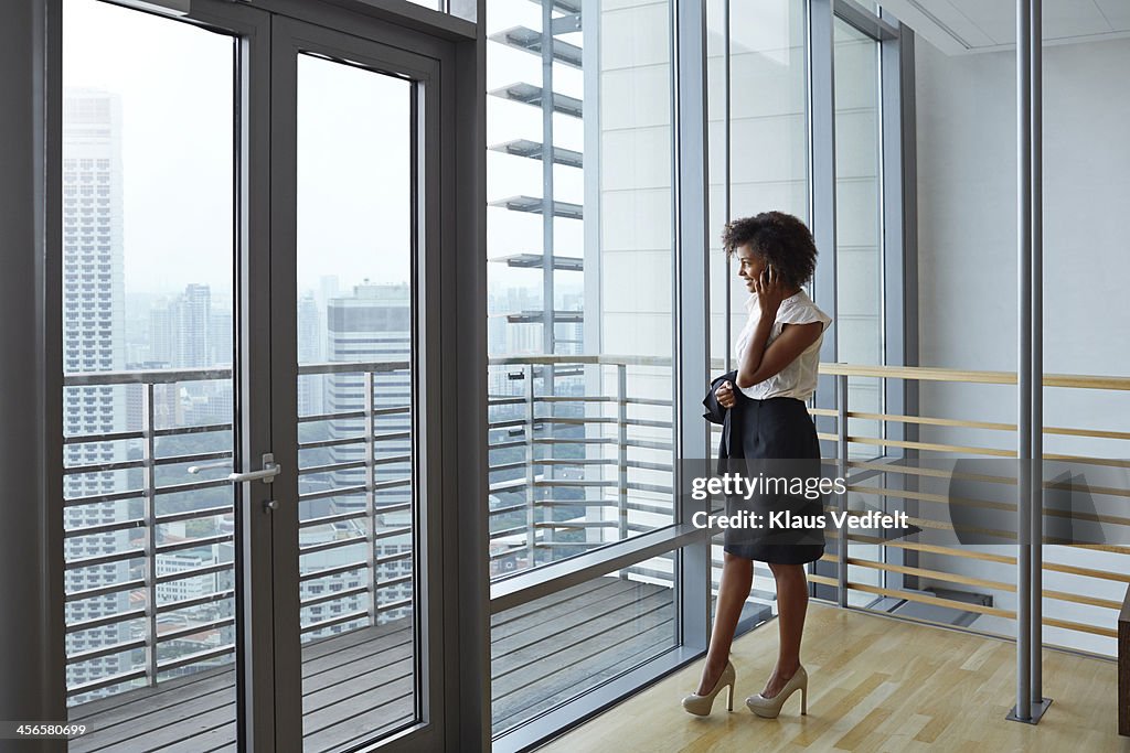 Businesswoman talking on phone & watching skyline