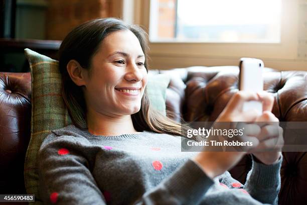 woman lying on sofa using smartphone. - chica salon movil fotografías e imágenes de stock