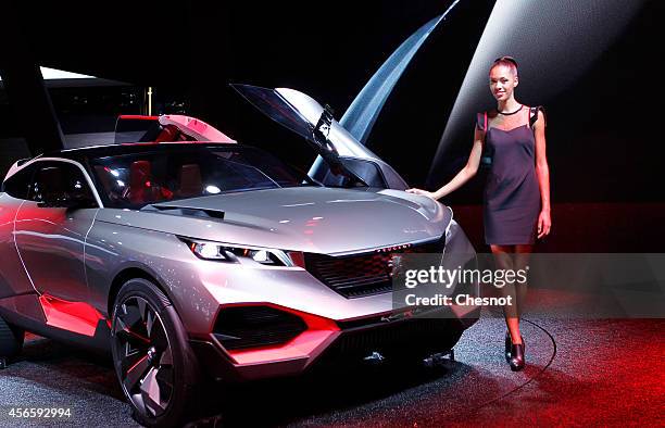 Model poses next a Peugeot concept car Quartz during the second press day of the Paris Motor Show on October 03 in Paris, France. The Paris Motor...
