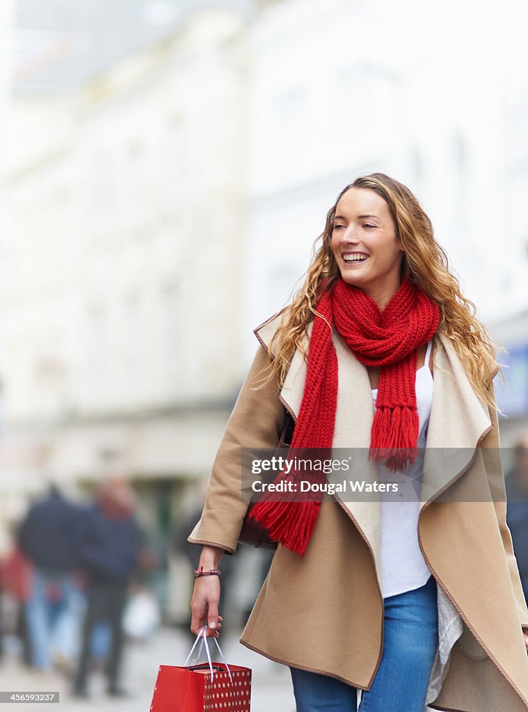 Woman in street carrying Christmas shopping.