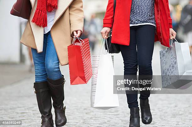 friends carry christmas shopping on a busy street. - geschenktüte einwickelpapier stock-fotos und bilder