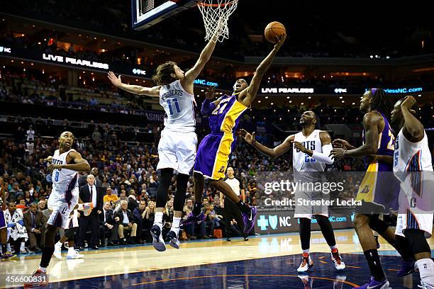 Kobe Bryant of the Los Angeles Lakers drives to the basket Josh McRoberts of the Charlotte Bobcats during their game at Time Warner Cable Arena on...