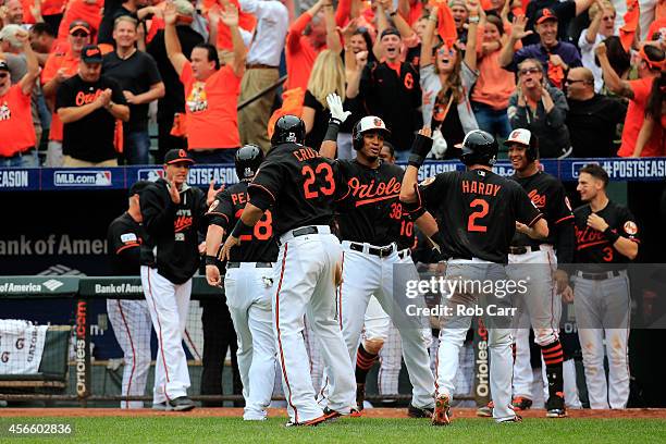 Hardy celebrates with his teammates Nelson Cruz and Jimmy Paredes after sliding safe to home plate to score the go ahead run on Delmon Young of the...