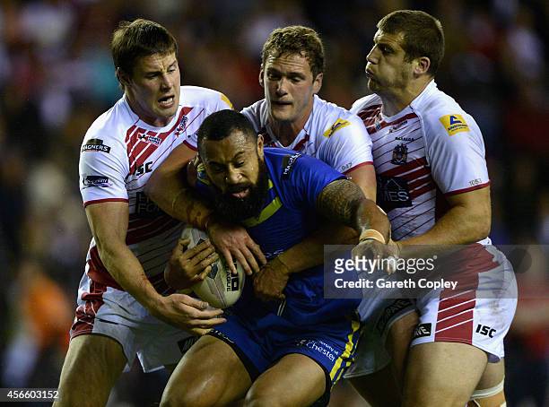 Roy Asotasi of Warrington Wolves is tackled by Joel Tomkins, Sean O'Loughlin and Tony Clubb of Wigan Warriors during the First Utility Super League...