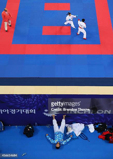 Kazakhstan athlete rests in the athlete waiting area as Tsui Ping Ku of Chinese Taipei and Thi Khanh Tran of Vietnam compete in the Women's -50kg...