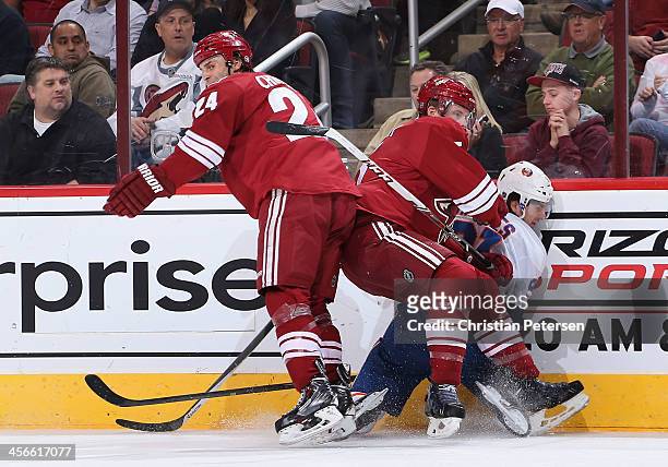 Kyle Chipchura and Connor Murphy of the Phoenix Coyotes collide with John Tavares of the New York Islanders during the NHL game at Jobing.com Arena...