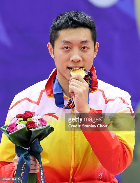 Xu Xin of China bites his Gold Medal during the victory ceremony after he defeated his compatriot Fan Zhendong during the Men's Singles Gold Medal...