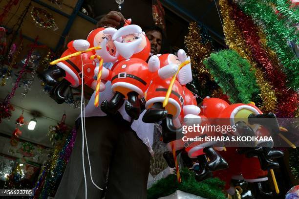 Sri Lankan vendor hangs inflatable Santa Claus toys for sale at a market ahead of Christmas Day in Colombo on December 15, 2013. Christians account...