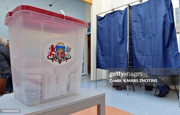 Ballot box with the Latvia's coat of arms is seen at a polling station as voters sit inside polling booths during general elections in Riga on...