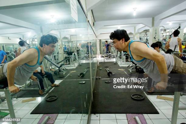 Wasiq, an ethnic Hazara from Ghazni, Afghanistan works out at a public gym, which charges 5 dollars a month on December 13, 2013 in Cisarua,...