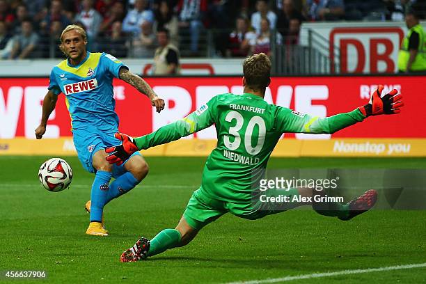 Marcel Risse of Koeln scores his team's first goal against goalkeeper Felix Wiedwald of Frankfurt during the Bundesliga match between Eintracht...