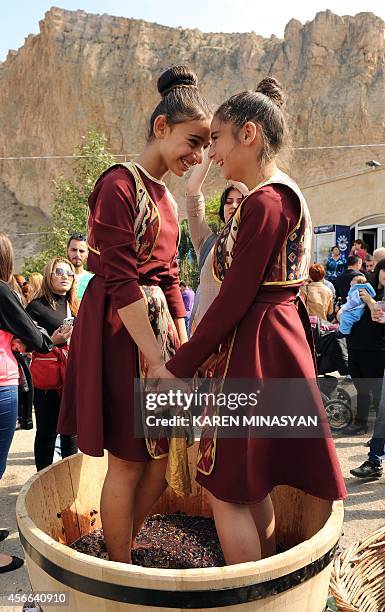 Two Armenian girls tramp grapes in order to make wine during a wine festival devoted to grape-gathering in the village of Areni on October 4, 2014....