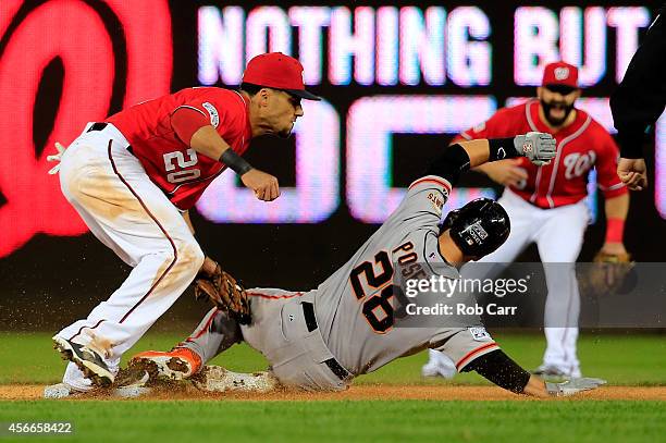 Buster Posey of the San Francisco Giants gets tagged out by Ian Desmond of the Washington Nationals after attempting to steal second base in the...