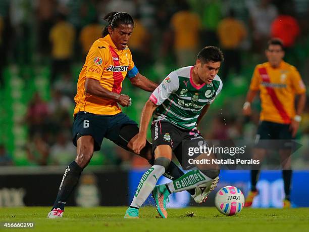 Javier Orozco of Santos tries to avoid the mark of Joel Huiqui of Morelia during a match between Santos Laguna and Morelia as part of 12th round...