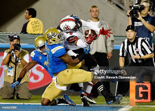 Wide receiver Des Anderson of the Utah Utes hangs on to the ball as he score s touchdown against Ishmael Adams and Fabian Moreau of the UCLA Bruins...