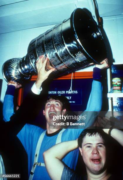 Wayne Gretzky of the Edmonton Oilers celebrates in the locker room with Joey Moss and the Stanley Cup Trophy after the Oilers defeated the...