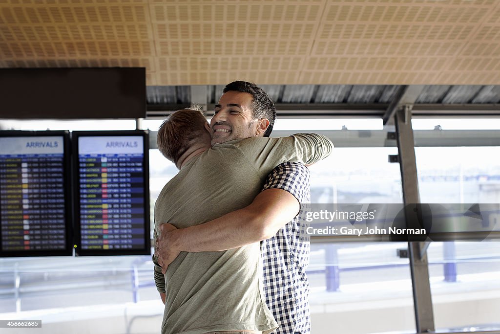 Two gay men embracing at airport