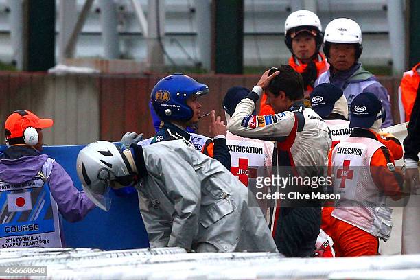 Distressed Adrian Sutil of Germany and Sauber F1 speaks to a Doctor whilst Jules Bianchi of France and Marussia receives urgent medical attention...