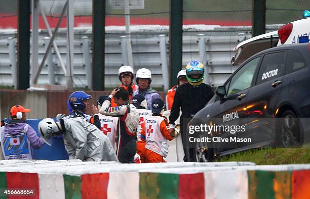 Distressed Adrian Sutil of Germany and Sauber F1 speaks to a Doctor whilst Jules Bianchi of France and Marussia receives urgent medical attention...