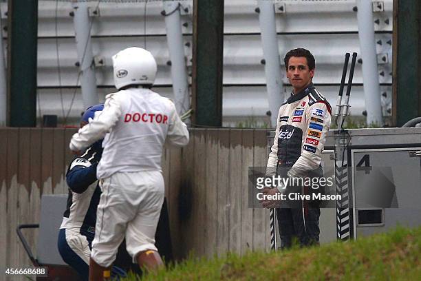 Distressed Adrian Sutil of Germany and Sauber F1 looks on whilst Jules Bianchi of France and Marussia receives urgent medical attention following a...